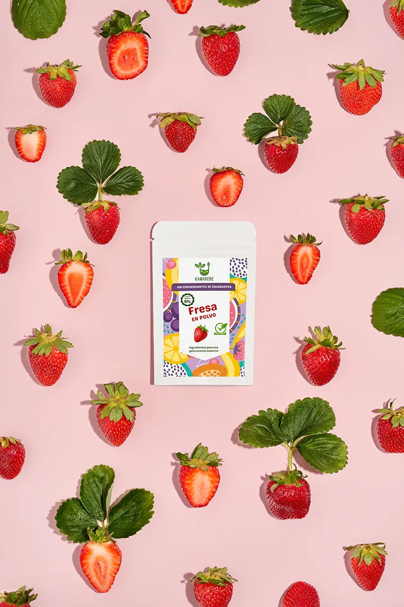 A commercial photograph of Kamarere’s 100% natural dehydrated fruit and vegetable powder in a resealable white pouch. The colorful label features a modern, vibrant fruit and vegetable pattern with the Kamarere logo at the top. The packaging highlights its preservative-free and additive-free composition, emphasizing its use for innovative cooking and gastronomy. The label includes an illustration representing fresh ingredients, reinforcing its natural origin.